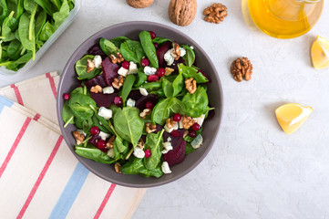 Salad with young spinach, boiled beets, blue cheese, nuts, cranberries in a bowl on a light background. Tasty diet fitness dish. Vitamin salad. Proper nutrition. Top view.