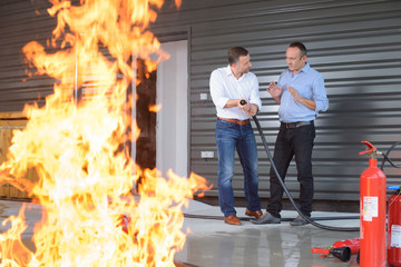 men and fire-extinguisher on flame background