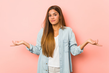 Young slim woman doubting and shrugging shoulders in questioning gesture.