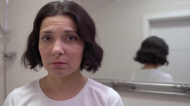 Sad middle-aged woman looking at cam, unhappy with wrinkles on skin, bad mood