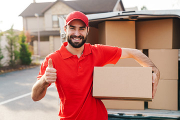 Image of delivery man standing with parcel box and showing thumb up