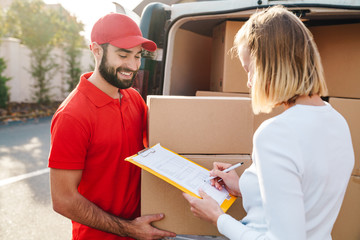 Image of cheerful delivery man giving order to caucasian woman