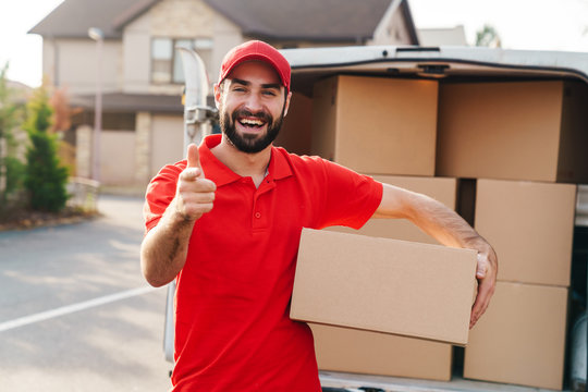 Image Of Delivery Man Holding Parcel Box And Pointing Finger At Camera