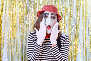 girl dressed in mime with red hat, red bow tie, striped shirt and white gloves.