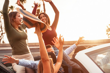 Happy friends having fun on convertible car in road trip - Group young people enjoying vacation...