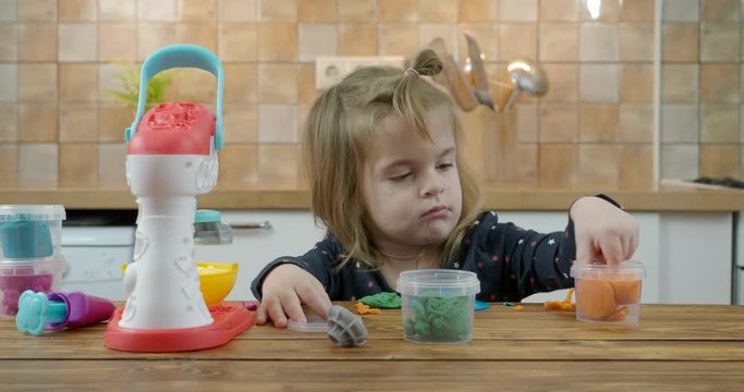 Little baby girl playing with colorful dough 