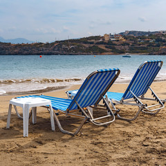 two sun loungers on the sandy beach of the Greek resort town of Agios Nikolaos