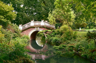 Bridge and river with water reflections in Parc Monceau. Paris, France.