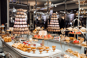 Candy bar with balls, macaroon, candy bar on holiday, candy bar at the wedding. Plate with marshmallow cake in a candy bar. Colorful cakes collage. Dessert table for a party. 