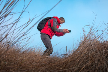 An experienced photographer takes pictures in nature. A professional video maker shoots scenes.