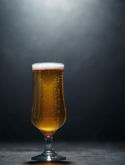 A glass of cold light beer lager on a dark background