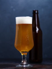 Cold Beer lager glass and beer bottle on a dark background close up with water drops
