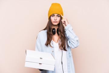 Young caucasian woman holding pizzas isolated pointing temple with finger, thinking, focused on a task.