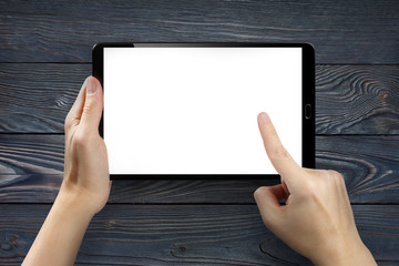 Hands touching blank screen of tablet computer on dark wooden background