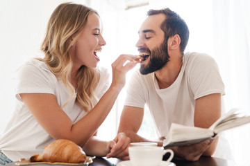 Happy beautiful young couple having breakfast at the kitchen table