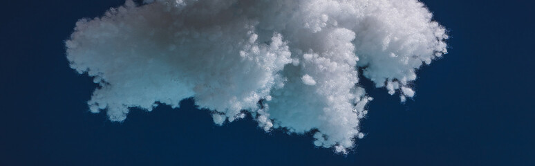 white fluffy cloud made of cotton wool isolated on dark blue, panoramic shot