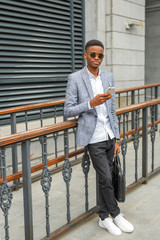 handsome young african man in a suit with a phone in his hand