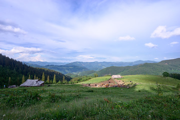 Fototapeta na wymiar Beautiful summer mountains landscape with green pastureland view and old wooden house. Carpathians, Ukraine.