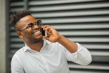 handsome young african man in a white shirt with a phone in his hand