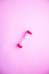 hourglass on pink background with white sand inside
