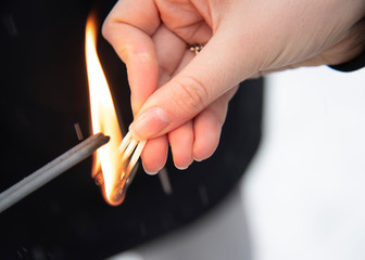 A woman's hand with three burning matches ignites sparklers.