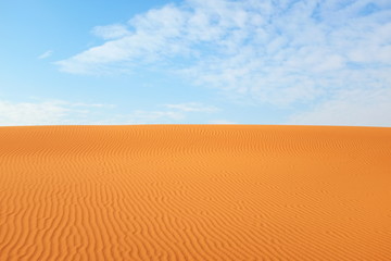 Desert summer background of bright orange desert sand and clear blue sky