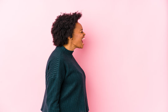 Middle Aged African American Woman Against A Pink Background Isolated Shouting Towards A Copy Space