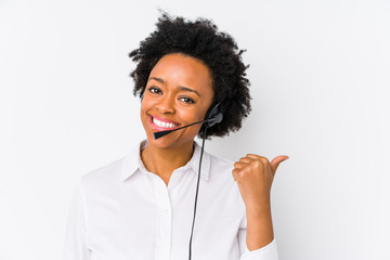 Young african american telemarketer woman isolated points with thumb finger away, laughing and...