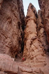 Caucasian male traveler in a red T-shirt posing on a background of sandy rock Solomon Pillars in Timna National Park, Israe