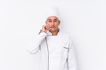 Young latin chef man isolated with fingers on lips keeping a secret.