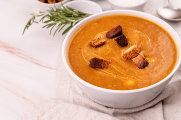 Pumpkin soup with croutons in white bowl