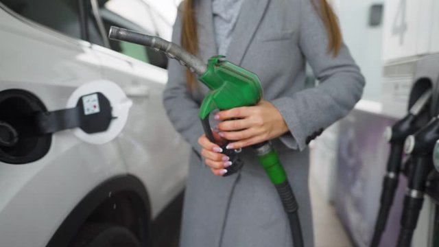 Woman fills petrol into her car at a gas station close-up
