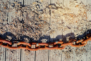 Old rusty chain on textured wooden deck.