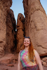 Caucasian woman hippie red-haired traveler with glasses posing on a background of sandy rock Solomon pillars in Timna National Park, Israel,