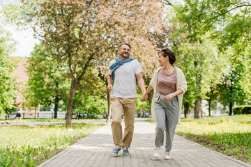 Obraz premium Middle-aged couple posing at the camera on the park's path.