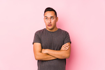 Fototapeta premium Yooung latin man posing in a pink backgroundtired of a repetitive task.