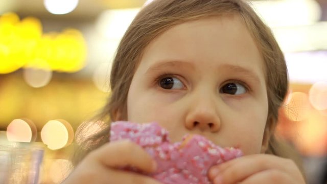 Child eats donut. Closeup baby girl eating doughnut with glase. Delicious, sweet, sweettooth.