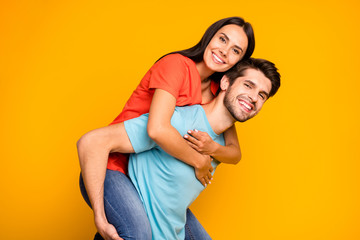 Profile photo of two charming people guy carrying lady piggyback meet summer adventures together wear casual stylish blue orange t-shirts jeans isolated yellow color background