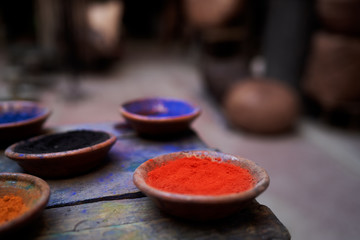 Travel by Morocco. Plates with natural colorful paint powder on wooden table.