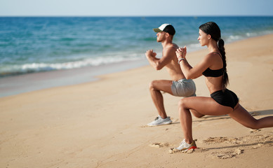 Healthy lifestyle. Young beautiful couple doing sports exercises at the beach.