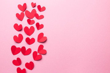 A lot of small hearts of red color against on a pink background. Happy Valentine's Day.