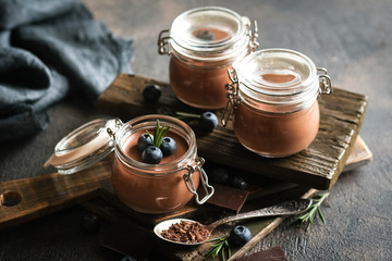 Chocolate mousse in glass jar with berries on a dark background copy space. Homemade dessert.