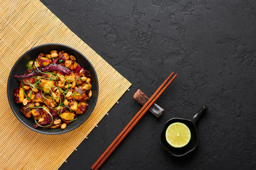 Kung Pao Paneer at black slate background. Kung Pao Paneer is a vegetarian version of chinese sichuan dish Gong Bao with paneer cheese, peanuts, chilli peppers, sauces and onion. Top view. Copy space