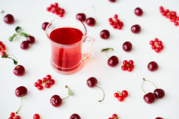 Glass cup of fruit tea on white backgrund with red berries.