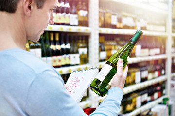 Man chooses bottle of white wine in store