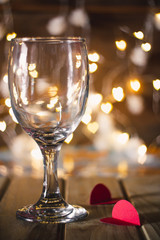 A glass of wine on a wooden table with bokeh lights as a background for the Valentine concept.
