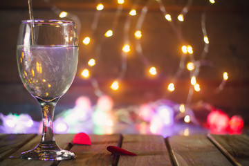 A glass of wine on a wooden table with bokeh lights as a background for the Valentine concept.