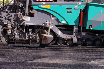 Heavy asphalt laying machine during work. Road construction.