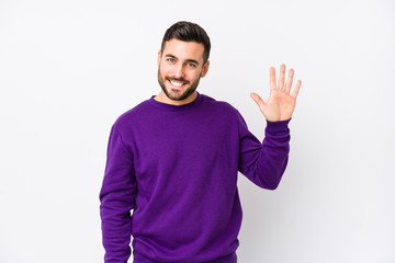 Young caucasian man against a white background isolated smiling cheerful showing number five with...