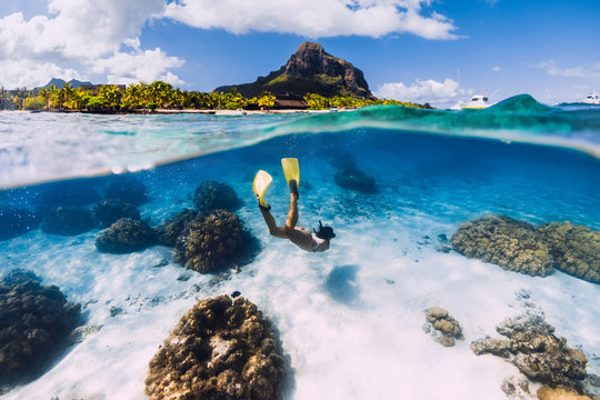Woman freediver glides over sandy sea with yellow fins in transparent sea. Freediving in Mauritius